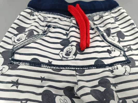 Detailaufnahme des roten Kordelzugs und der Mickey-Mouse-Motive auf der gestreiften Jogginghose
