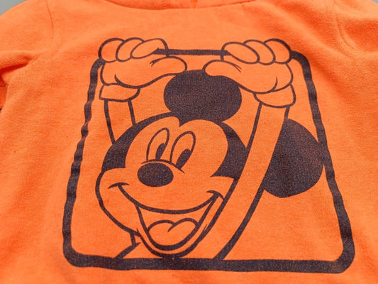 Detailansicht des Mickey-Mouse-Motivs auf einem orangen Disney-Hoodie in Größe 86