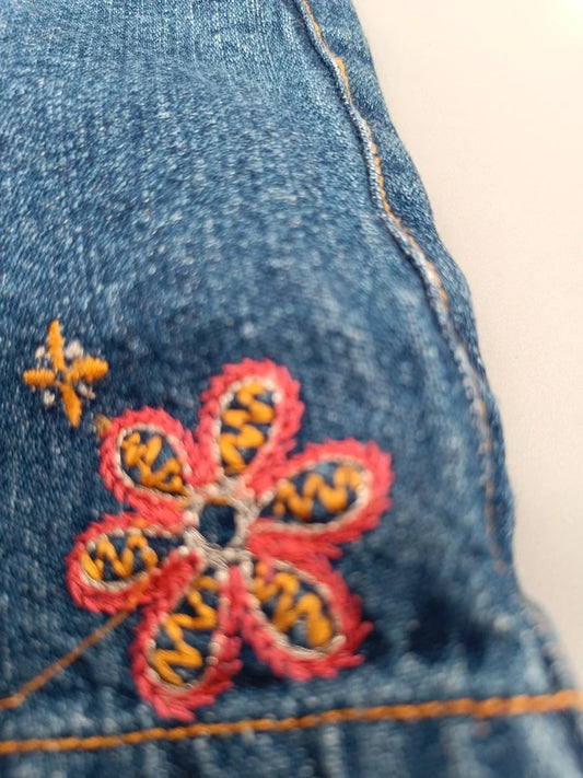 Detailaufnahme der bunten Blumenstickerei auf blauen Jeansshorts, Größe 92