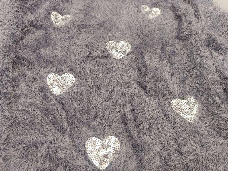 Nahaufnahme der aufgenähten silbernen Paillettenherzen auf flauschigem Stoff