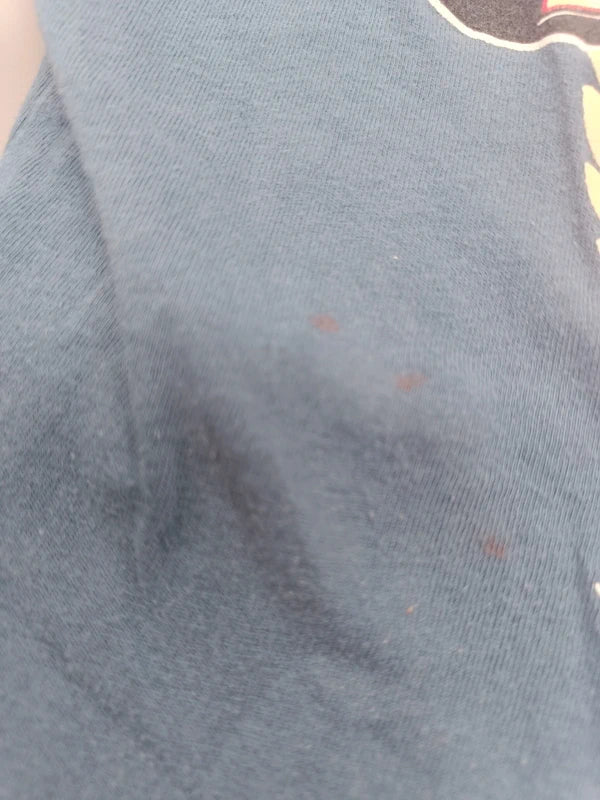 Detail der kleinen Flecken auf der Vorderseite des blauen T-Shirts