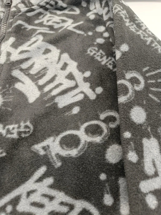 Detailaufnahme des hellgrauen Graffiti-Alloverprints auf der dunkelgrauen Jungen-Fleecejacke in Größe 134