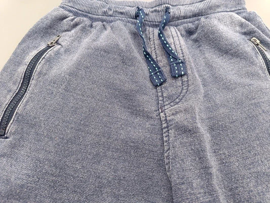 Detailaufnahme des Kordelzugs und der seitlichen Reißverschlusstaschen der grauen Jungen-Sweatshorts in Größe 128