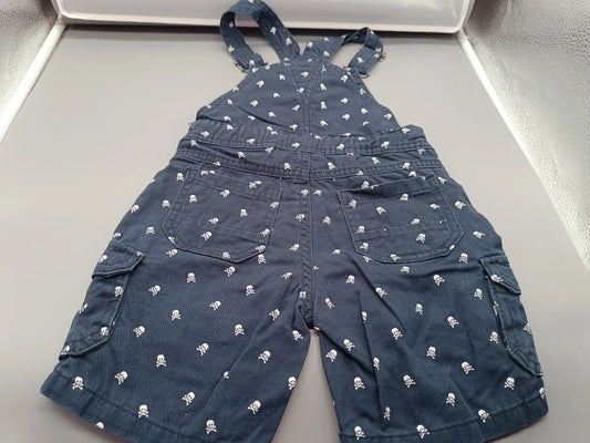 Dunkelblaue Jungen-Latzshorts mit weißem Totenkopfprint, verstellbaren Trägern und Cargotaschen in Größe 110, Vorderseite