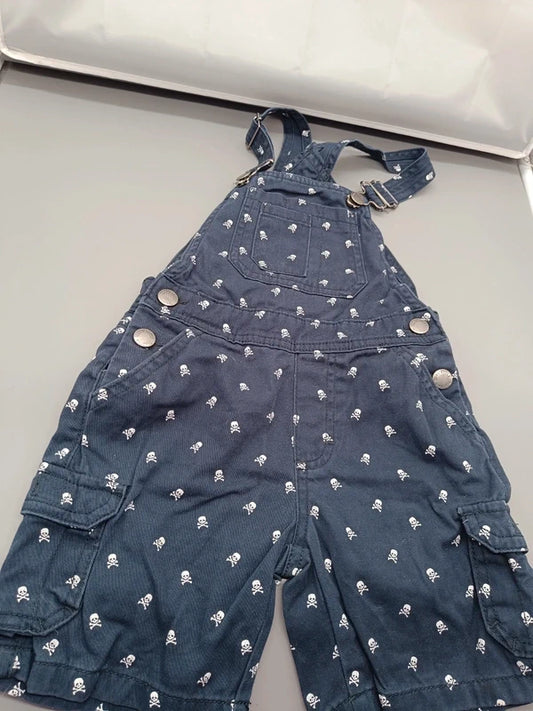 Detailaufnahme des weißen Totenkopfprints auf den dunkelblauen Jungen-Latzshorts in Größe 110