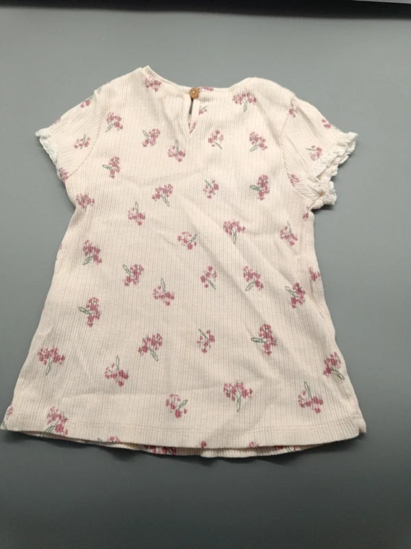 Rückseite des beigefarbenen Blumen-T-Shirts mit Knopf am Ausschnitt