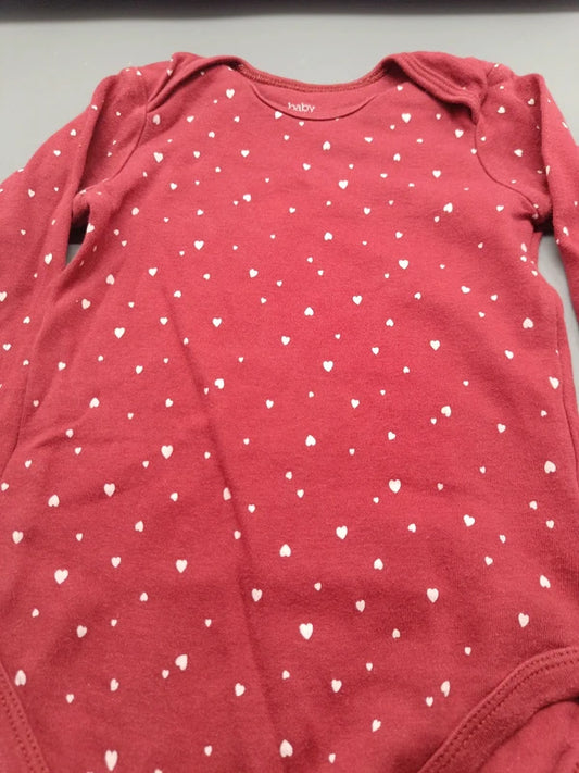 Detailaufnahme des weißen Herzmusters auf dem weinroten Baby-Langarmbody in Größe 92