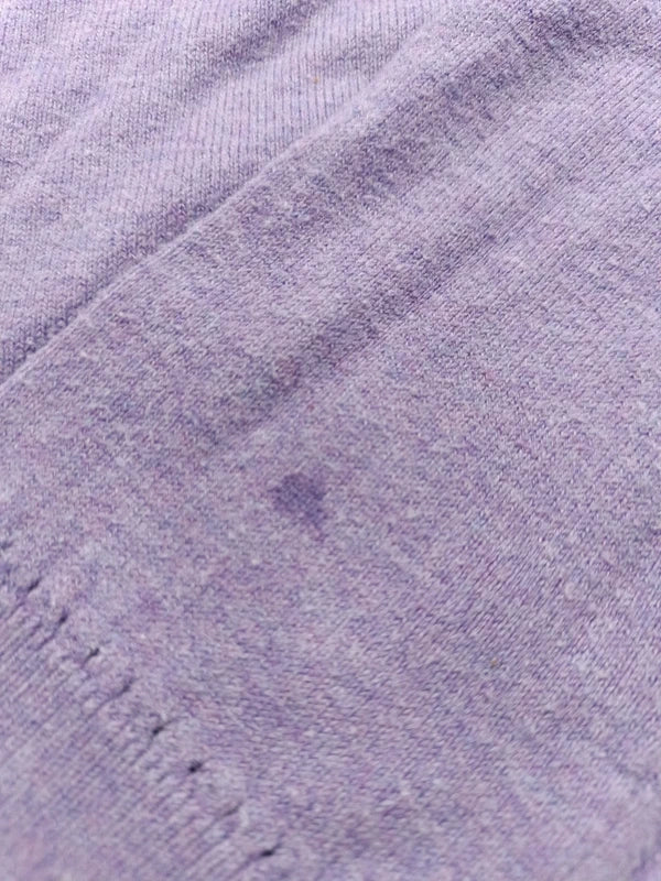 Detailaufnahme des kleinen Flecks an einem Ärmel des fliederfarbenen Pullovers