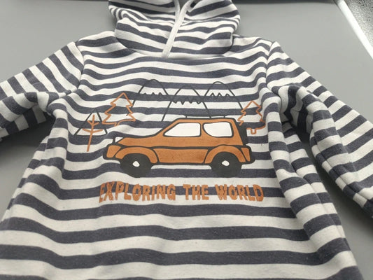 Detailaufnahme des orangefarbenen Auto-Motivs und des Exploring-the-World-Schriftzugs auf dem grau-weiß gestreiften Jungen-Hoodie in Größe 92