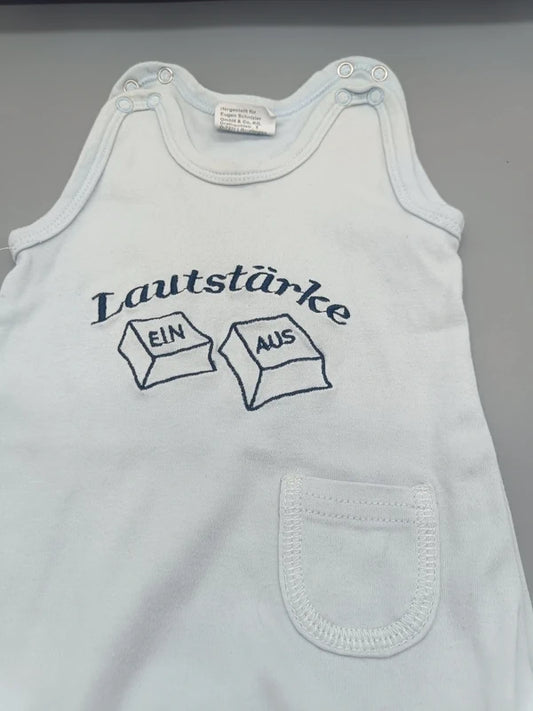 Detailansicht des Lautstärke EIN/AUS-Motivs auf dem weißen Baby-Strampler