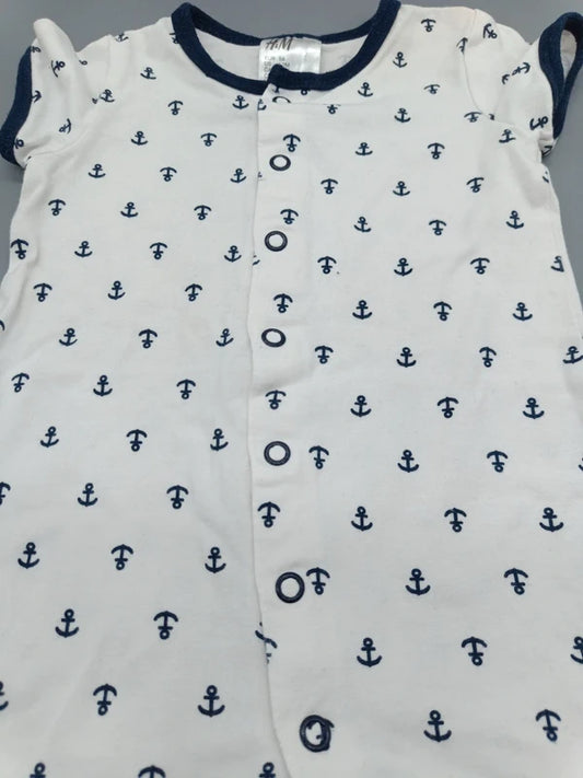 Detailansicht der Druckknopfleiste und des Ankermusters am weißen Baby-Overall