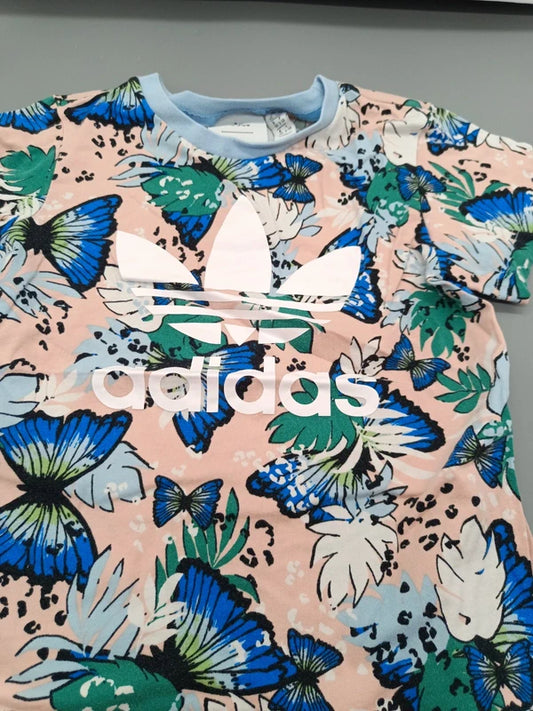 Detailansicht des adidas-Logos und bunten Schmetterlingsmusters auf dem Kinder-T-Shirt