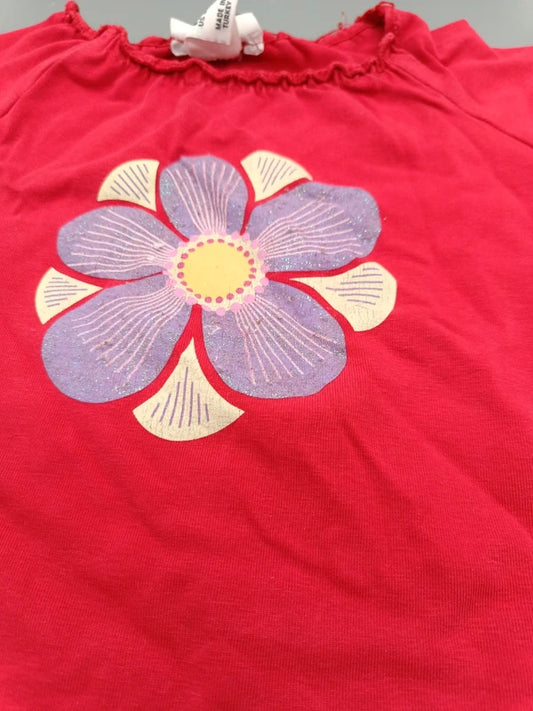 Detailaufnahme des lila-cremefarbenen Blumenmotivs auf dem pink-roten Mädchen-Shirt