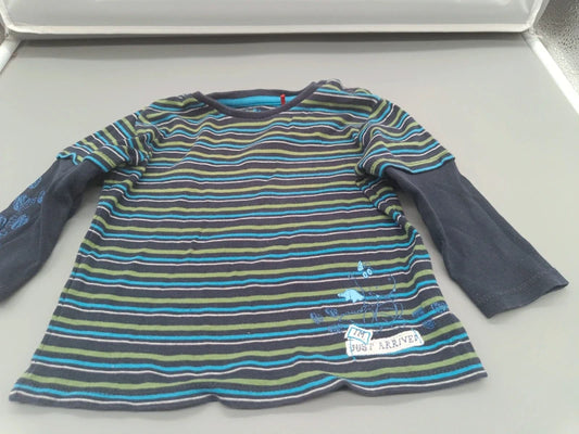 Detailaufnahme der türkis-weiß-olivfarbenen Streifen und des Schriftzugs auf dem dunkelblauen Langarmshirt