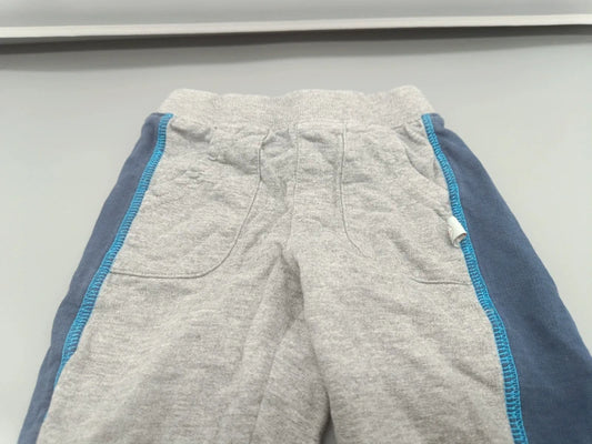 Detailaufnahme des elastischen Bundes, der Taschen und der türkisfarbenen Ziernähte an der grau-blauen Kinder-Jogginghose