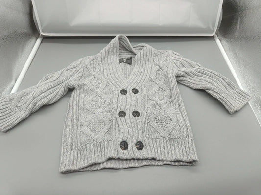 Detail des Schalkragens und der dunklen Knöpfe an der hellgrauen Strickjacke