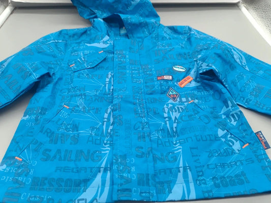 Detail der Aufnäher und des maritimen Musters auf der blauen Kinder-Regenjacke