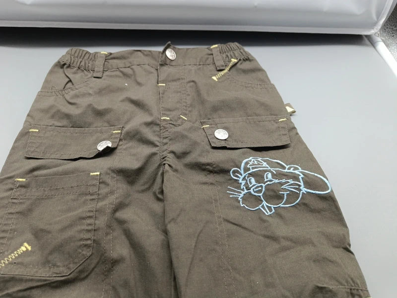 Detail des elastischen Bunds, der Zierklappen und des Tiermotivs auf der khakifarbenen Hose