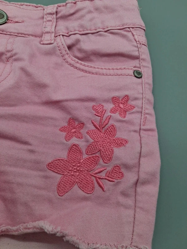 Detail der Blumenstickerei und Vordertasche der fliederfarbenen Shorts