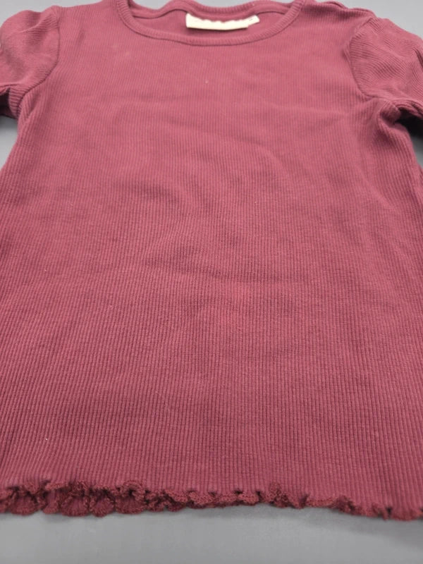 Rippstruktur und gewellter Saum des burgunderroten Langarmshirts