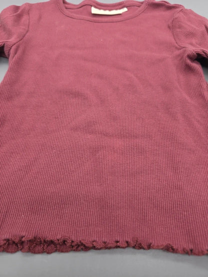 Rippstruktur und gewellter Saum des burgunderroten Langarmshirts