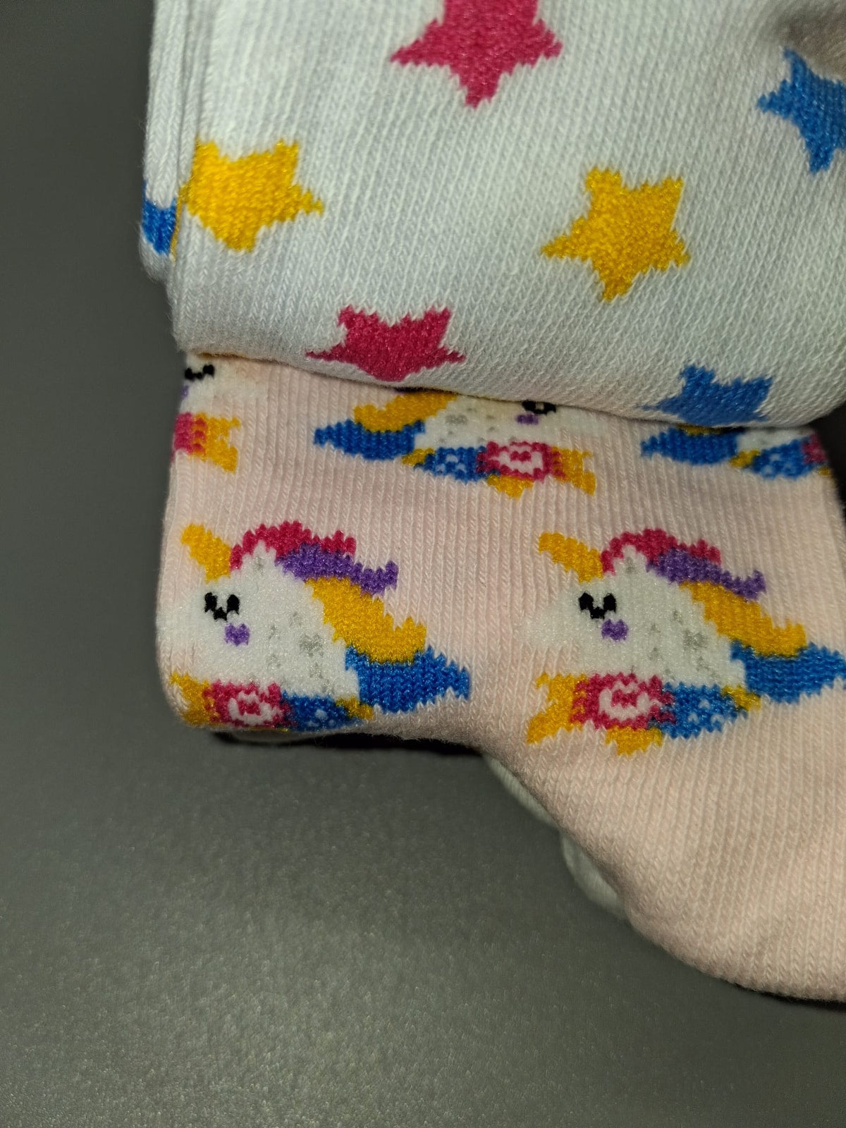 Detail von Kindersocken mit bunten Sternen und Einhörnern
