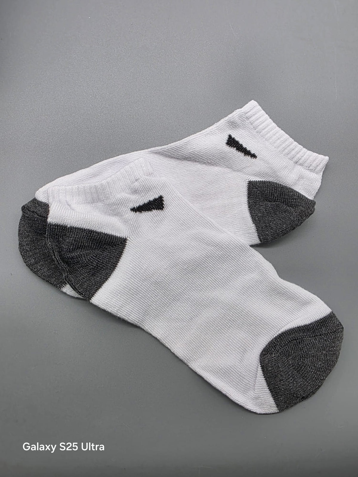 Ein Paar weiß-dunkelgraue Sneaker-Socken nebeneinander